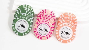Macro di fiches da poker in verde, rosa e arancione con valori numerici e corone