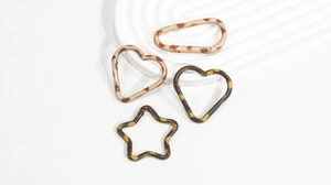 Dettaglio di ganci a molla in resina con stampa leopardata a forma di stella e cuore
