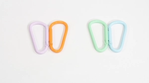 Macro detail of large D-shaped spring carabiners in purple, orange, mint, and blue finish
