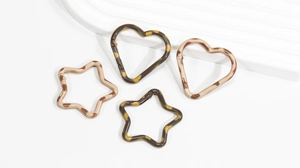 Dettaglio di moschettoni a molla a forma di cuore e stella con stampa leopardata