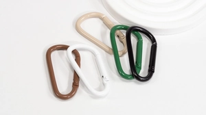 Close-up of five colorful D-shaped spring buckles with matte lacquer finish on white stone