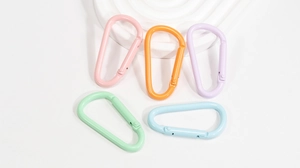 Five D-shaped spring carabiners in macaron pastel colors displayed on white pedestals
