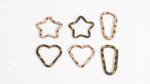 Dettaglio di ganci a molla leopardati a forma di stella, cuore e ovale per portachiavi