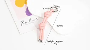 Dettaglio del portachiavi in pelle rosa intrecciata con cuciture fini e anello d'argento