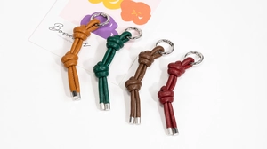 Dettaglio di quattro portachiavi in pelle intrecciata colorata con ganci in metallo