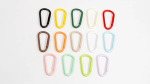 Macro shot of 14 colorful D-shape aluminum spring carabiner hooks in various lacquer finishes