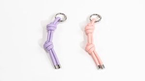 Dettaglio di portachiavi in pelle PU intrecciata viola e rosa con anelli in metallo argento