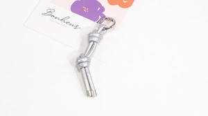 Dettaglio macro del portachiavi in pelle intrecciata argento con anello a molla e nodi