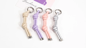 Dettaglio di portachiavi in pelle intrecciata color pastello con anelli metallici in quattro colori