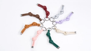 Dettaglio di portachiavi in pelle intrecciata in otto colori pastello con anelli argento