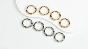Macro detail of rhinestone-inlaid round spring gate rings in gold and silver finish