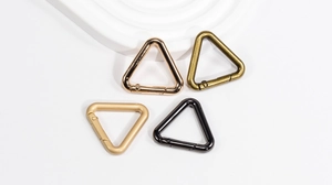 Macro shot of triangular spring snap hooks in four metallic finishes on white base