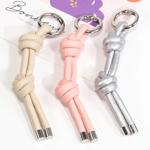 Portachiavi minimalisti in pelle intrecciata con clip metalliche in beige, rosa e argento
