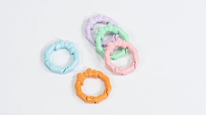 Five colorful bow-shaped spring ring connectors in macaron pastel shades on white background