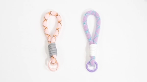 Detail von plüschigen Handy-Handgelenkschlaufen in rosa-orangen und lila-blauen Karomustern