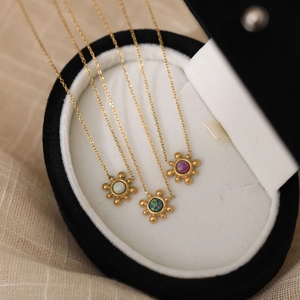 Detailed shot of 18K gold sunburst necklaces with colorful opal inlay in jewelry box