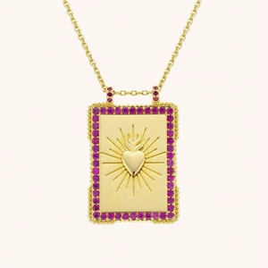 Close-up of golden tarot pendant with pink gems and radiant heart design details