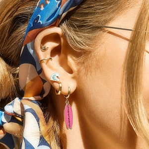 Detailopname van een roze surfplankoorbel met kristallen accenten en strandthema-bedels