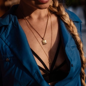 Collana a strati dorata con medaglione quadrato e ciondolo a croce indossata da modella