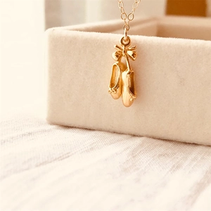 Collier avec pendentif chaussons de danse dorés et nœud sur boîte à bijoux velours