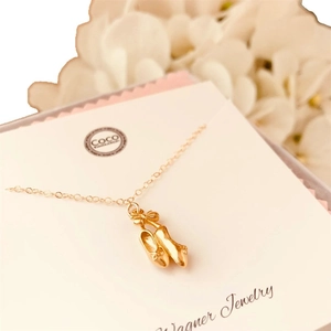 Collier doré avec pendentif ballerine et nœud délicat sur carte de présentation
