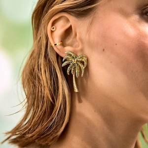 Gouden palmboom oorknopjes met groene strass steentjes op model voor zomerse strandlook