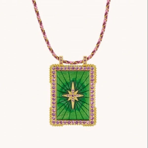 Macro shot of rectangular tarot pendant with green enamel, gold star and braided cord