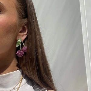 Detailopname van sprankelende kersenoorbellen met roze en groene kristallen bij model