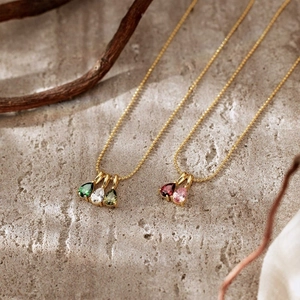 Macro shot of 18K gold-plated teardrop birthstone pendants on textured stone