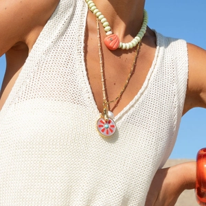 Dettaglio di una collana estiva a strati con ciondolo a conchiglia e fiore smaltato