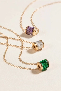 Detailed shot of three gold titanium steel necklaces with colorful cubic zirconia cylinders