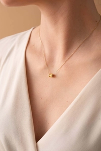 Detail of elegant gold chain necklace with amber zircon pendant on model neck