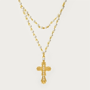 Macro-opname van gouden kruisketting met gedetailleerd snijwerk en witte parels