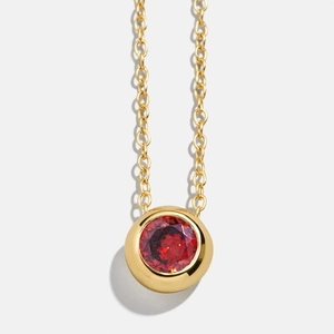 Classic gold necklace featuring a round red birthstone pendant with bezel setting