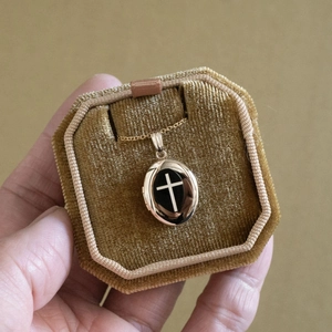 Macro-opname van een gouden ovale locket met kruis op een luxe fluwelen doosje