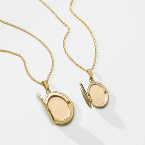 Minimalistische vergulde ovale medaillon ketting met open hart op witte achtergrond