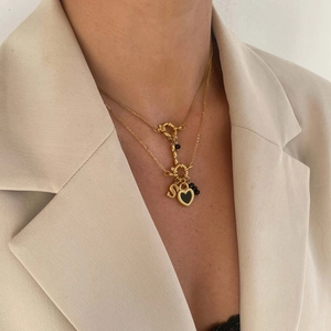 Vergulde ketting met letter S en zwart hartje hanger gedragen door een model