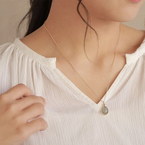 Detail van druppelvormige groene halfedelsteen hanger aan een vergulde dames ketting