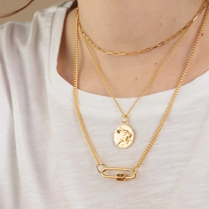 Detail of triple-layer gold necklaces featuring paperclip chain and lion coin pendant