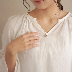 Minimalistische 18K vergulde titanium ketting met onregelmatige groene edelsteenhanger
