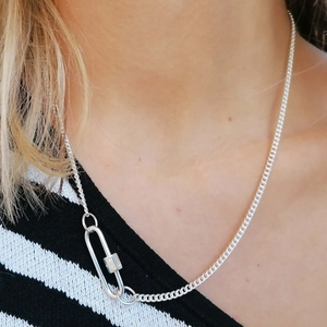 Close-up of a silver carabiner clasp and textured chain necklace on a model's neck