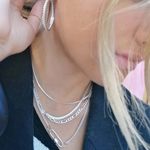 Detail of silver carabiner clasp and multi-layer chain necklaces worn on a model