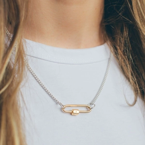 Detailed close-up of a two-tone carabiner necklace with a small star pendant on a white shirt