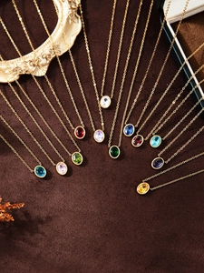 Gros plan de douze colliers de pierre de naissance colorés avec chaînes dorées en éventail