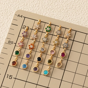 Gold flower and round birthstone pendants with colorful zircon crystals on a grid board