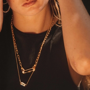 Detail of double-layer gold necklaces with LOVE bead and unique carabiner clasp