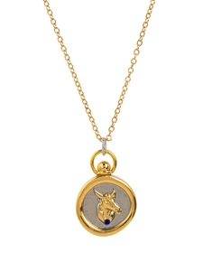 Close-up of dual-tone 18K gold zodiac pendant with embossed golden bull and blue gemstone