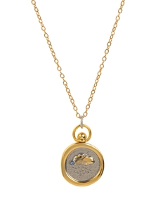 Detail of 18K gold necklace with a two-tone zodiac pendant and blue gemstone inlay