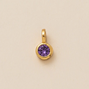 Detailed top view of a round purple zircon pendant with a polished gold metal clasp