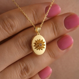 Dettaglio di un medaglione ovale dorato vintage con girasole e pietra preziosa